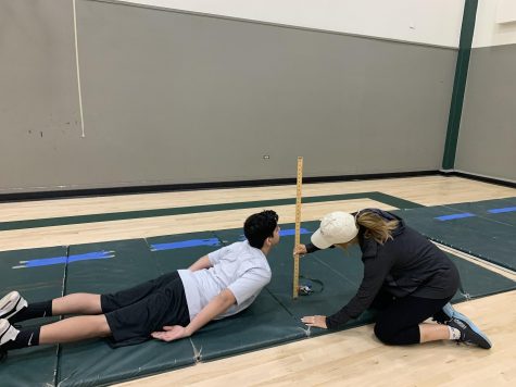 PE Teacher Shawna Virga measures a student's performance in the trunk lift for freshman fitness testing.