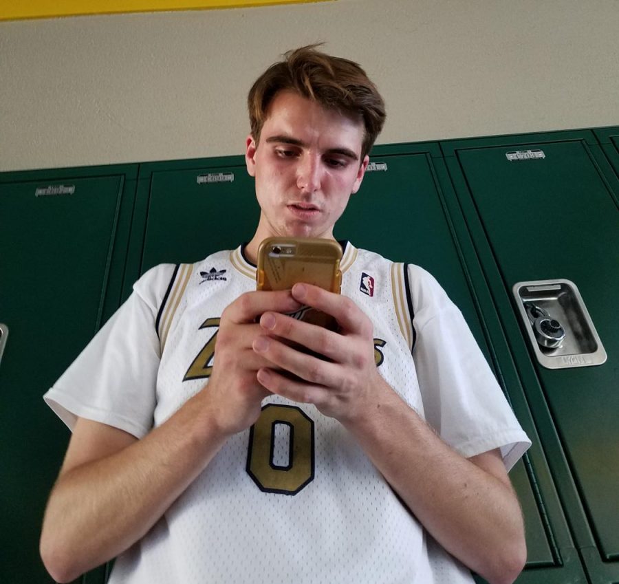 Senior Cade Johnson checking his social media networks during passing period in the hallway.