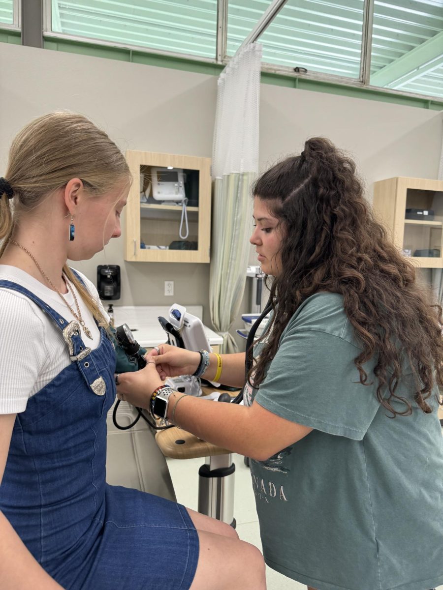 Coco Estrada takes a students' blood pressure.