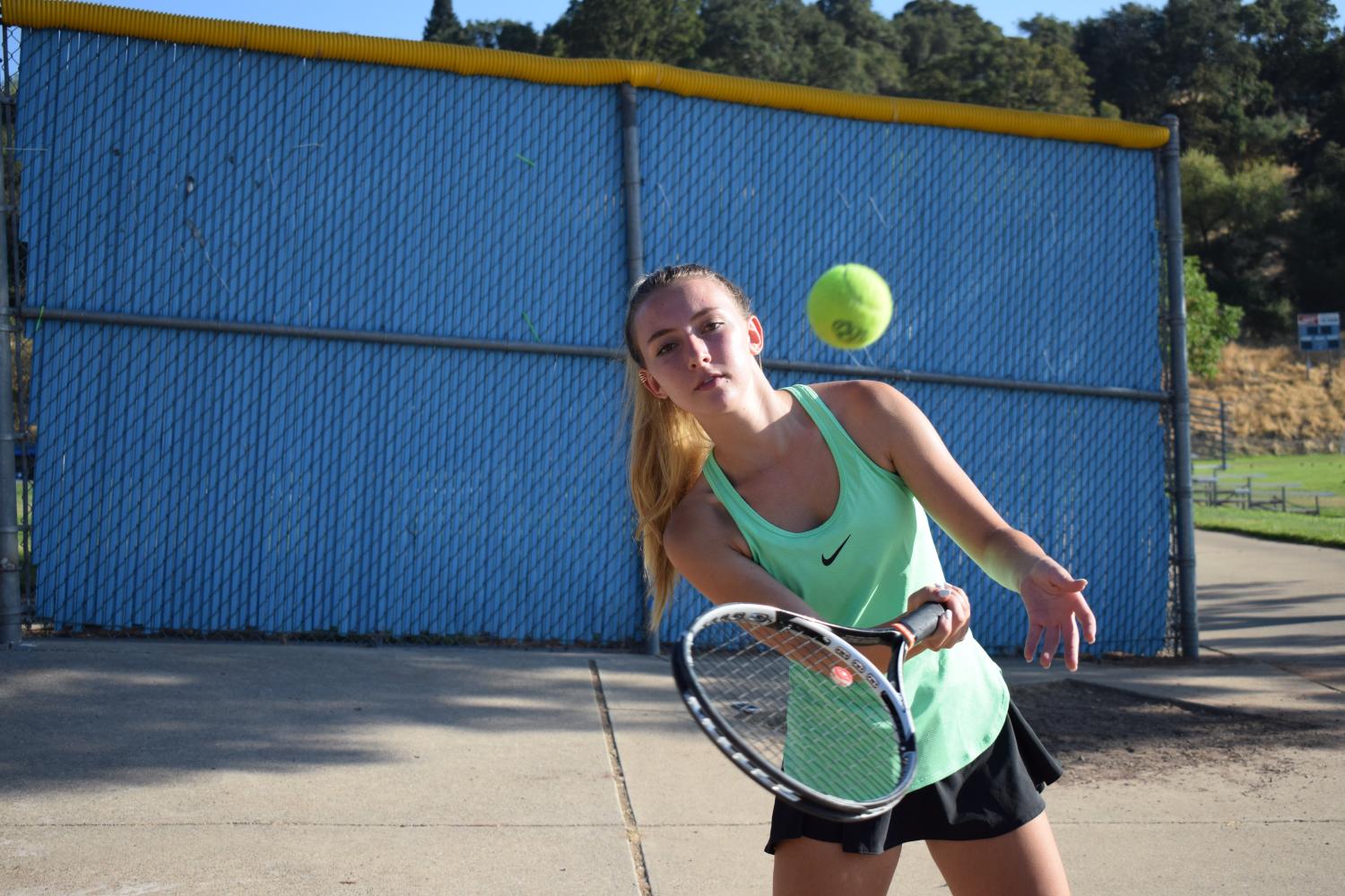 Junior Claire Chally warms up in her tennis match.