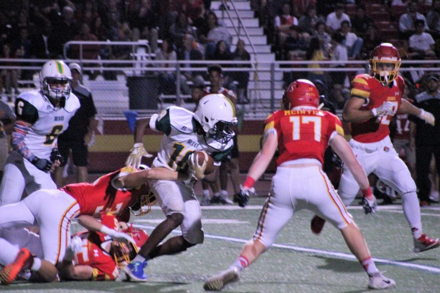 Micaiah Gautier pushes past Jesuit players while running the ball.