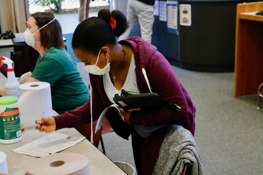 Senior Senait Syoum picks up a laptop in the Rio Americano High School library on April 1. The district passed out computers to students who wanted one in preparation for beginning distance learning April 13.