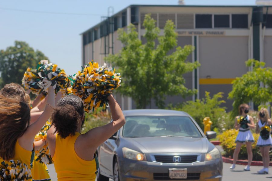 The cheer team waves their pom-poms at passing seniors.