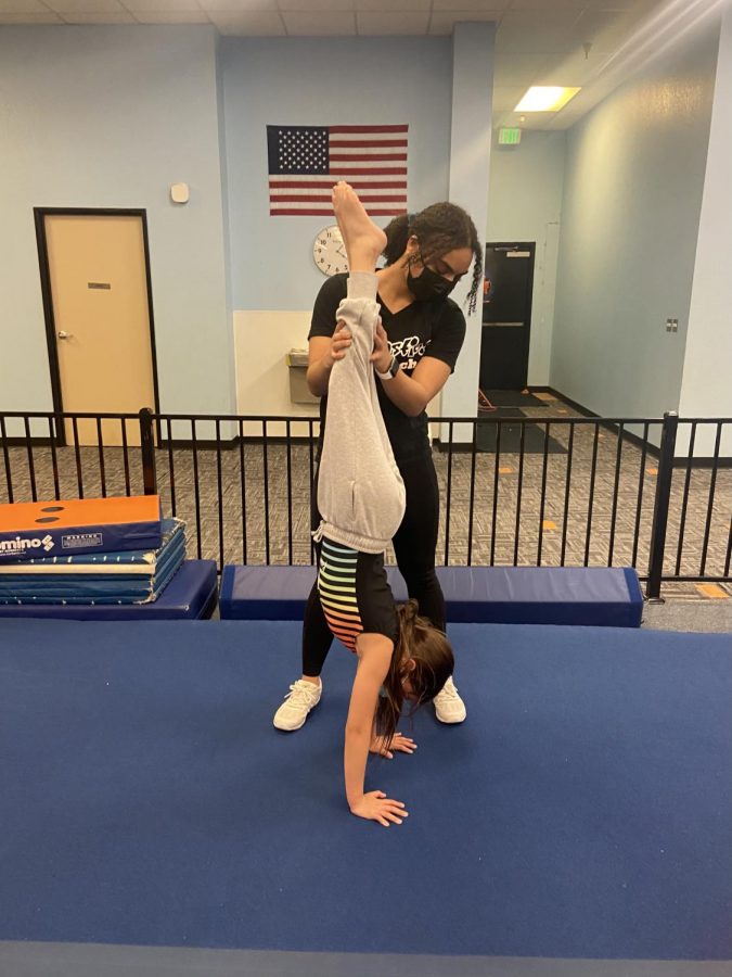 Senior Elise Ezekiel assists one of her gymnasts with a handstand.